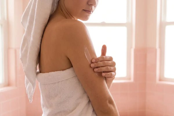 Femme appliquant une crème sur l'arrière du bras, routine contre la kératose pilaire