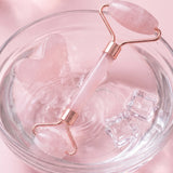 Gua sha et rouleau rose rafraîchis dans un bol d'eau glacée
