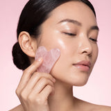 Femme massant sa pommette avec un gua sha rose