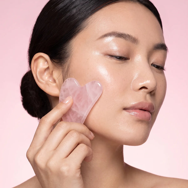 Femme massant sa pommette avec un gua sha rose