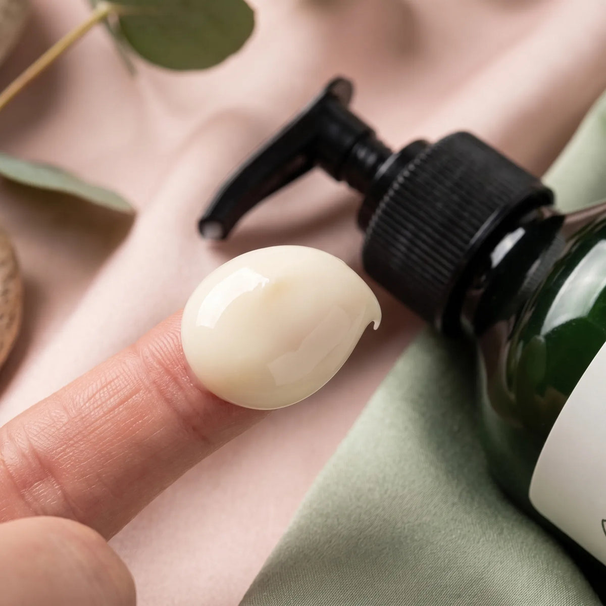 Texture ivoire fraîche et fondante de la crème hydratante corps Glowy sur le bout du doigt